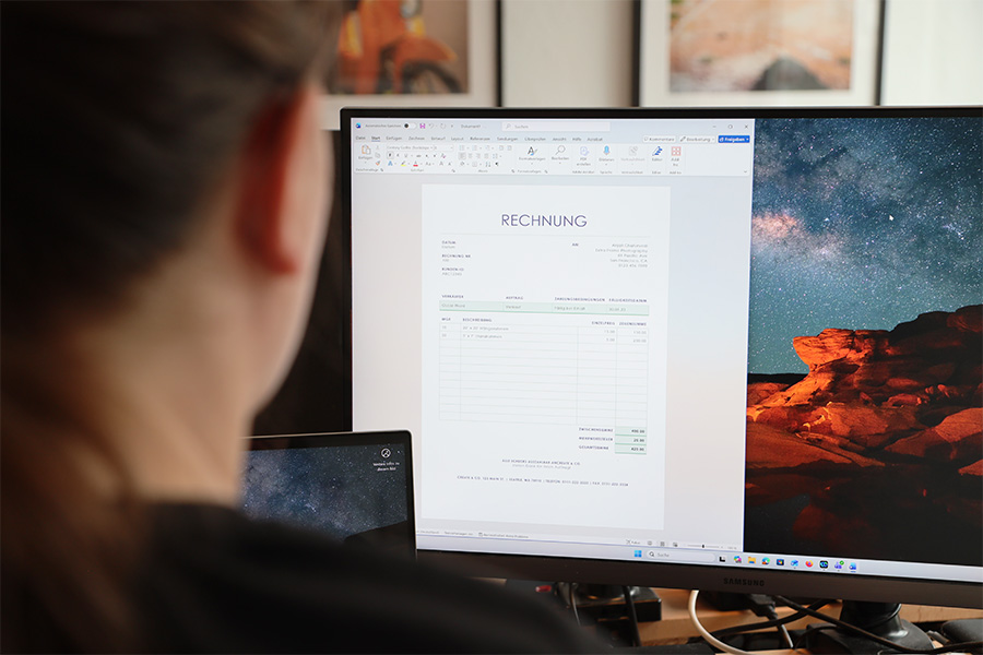 Eine Frau arbeitet an einem PC. Auf dem Monitor sieht man eine Word Vorlage